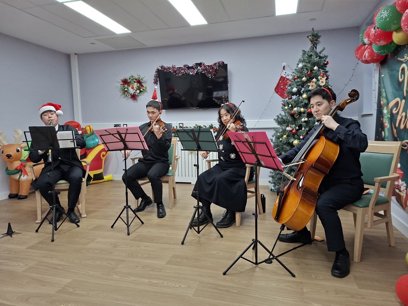 A clarinettist and three string players performing in a care setting at Christmas