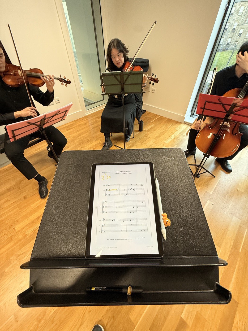 A string trio rehearsing behind a part on a music stand