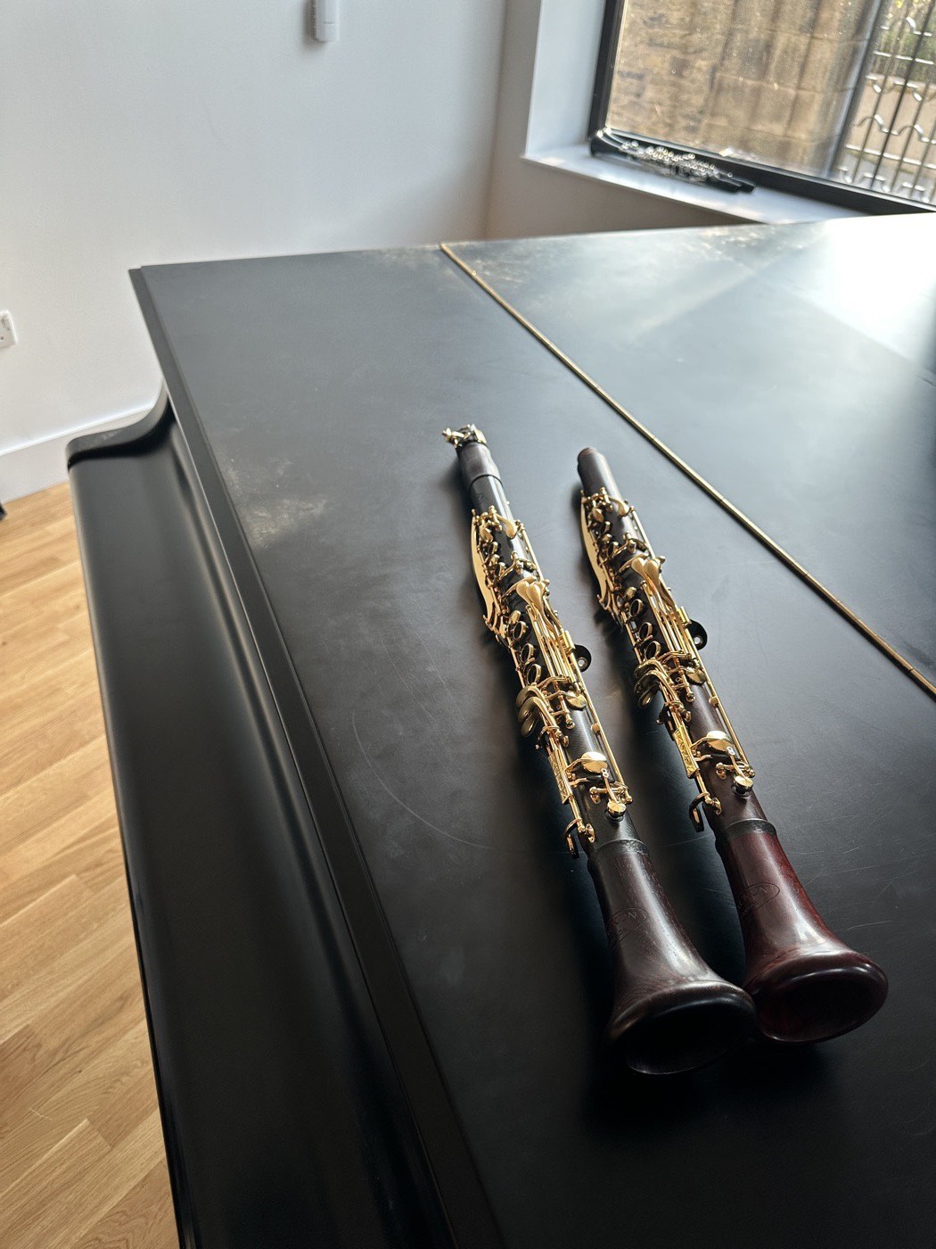 Two clarinets resting on the lid of a piano